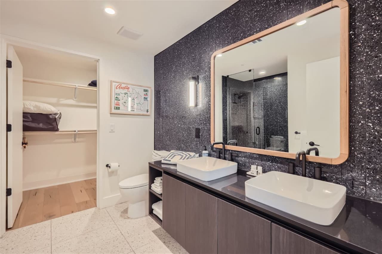 En-suite bathroom with double vanity sinks and a walk in closet.
