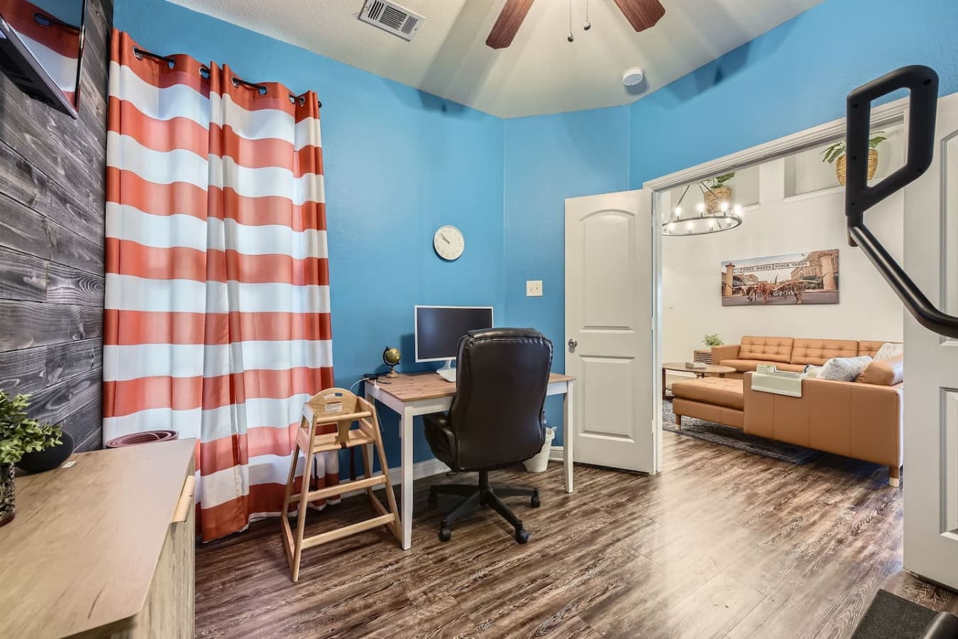 Just off the living room, a dedicated office space awaits, complete with a desk, elliptical machine, and Apple TV—perfect for remote work or staying active.