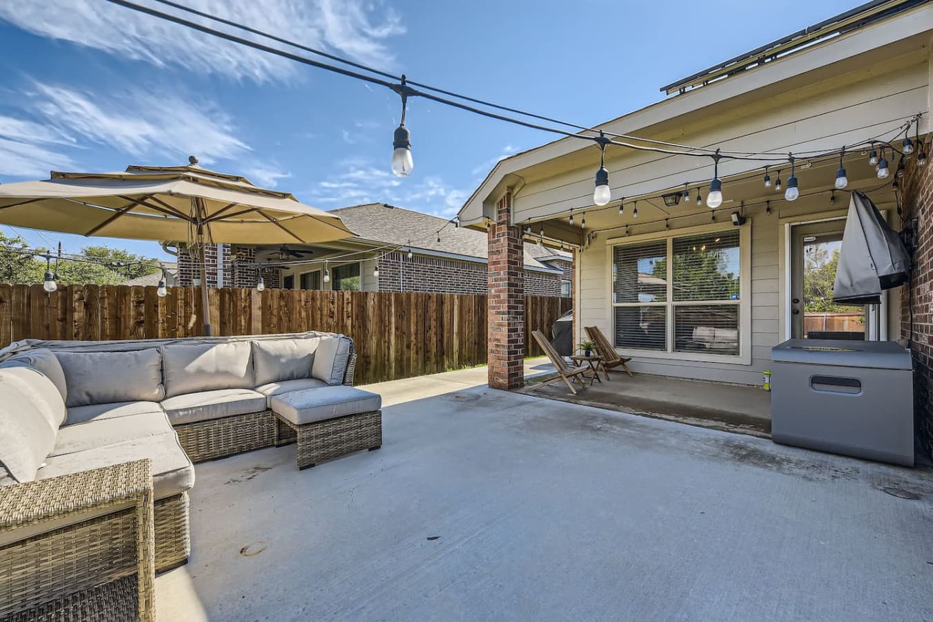 String lights and a large outdoor sectional featured in the backyard space.