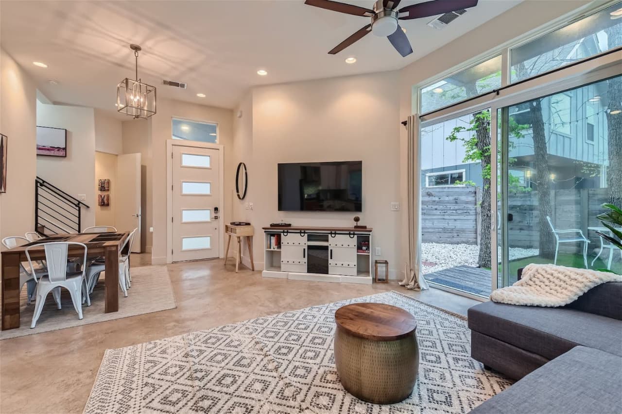 The living room features a plush sectional and armchair, providing plenty of seating for everyone to relax and watch a movie on the large Smart TV.