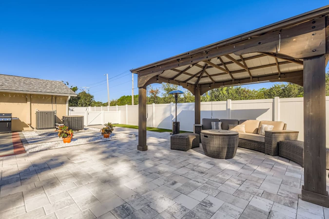 Relax in style under the covered gazebo, this private backyard oasis features cozy seating and elegant pavers, perfect for lounging day or night.