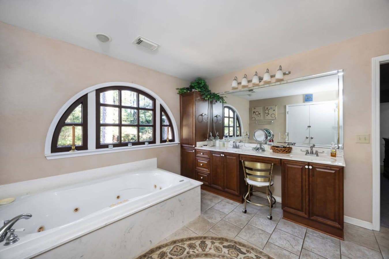 A warm bathroom featuring a soaking tub and a wide vanity for getting ready.