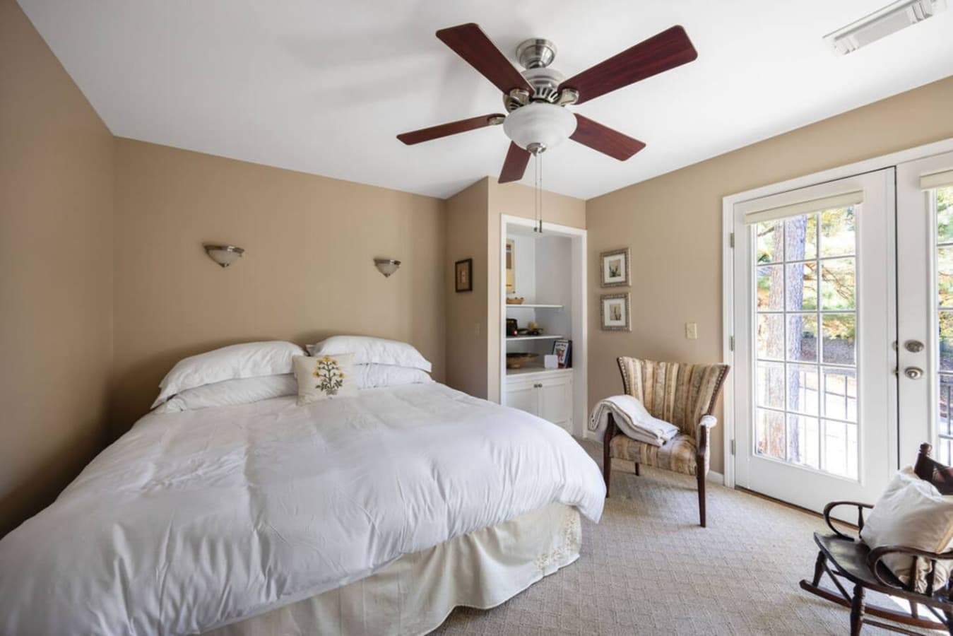 A bright bedroom with classic furnishings and direct access to outdoor views.