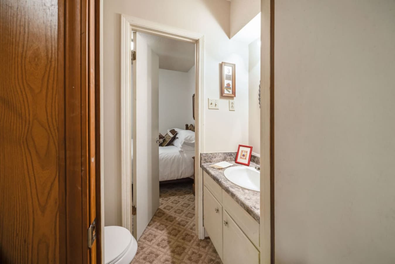 A simple bathroom with a clean vanity and easy access to the adjoining bedroom.