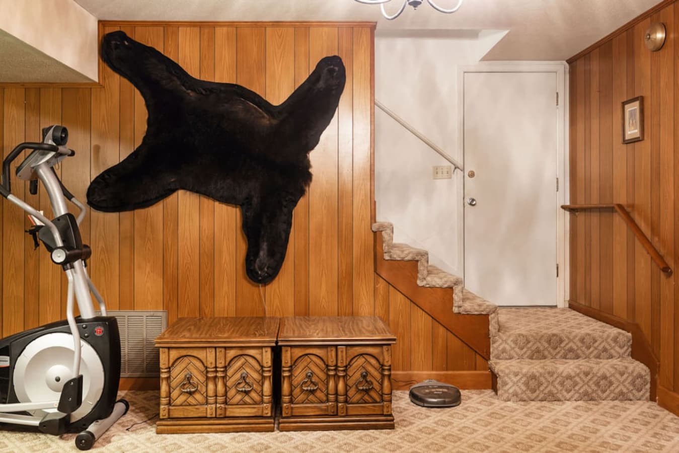 A rustic lower level space with wood paneling and a convenient stairway entrance.