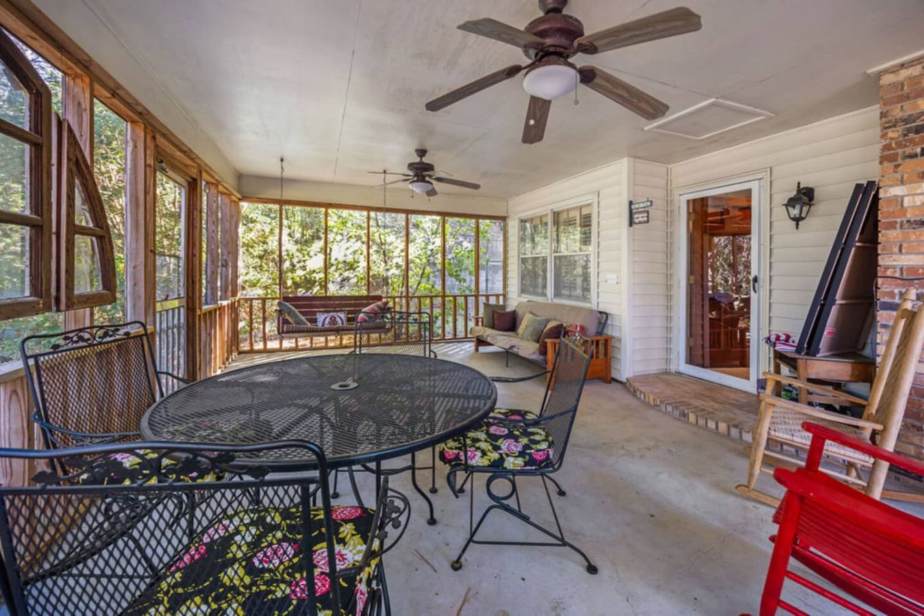 A spacious screened porch with comfortable seating and views of the trees.
