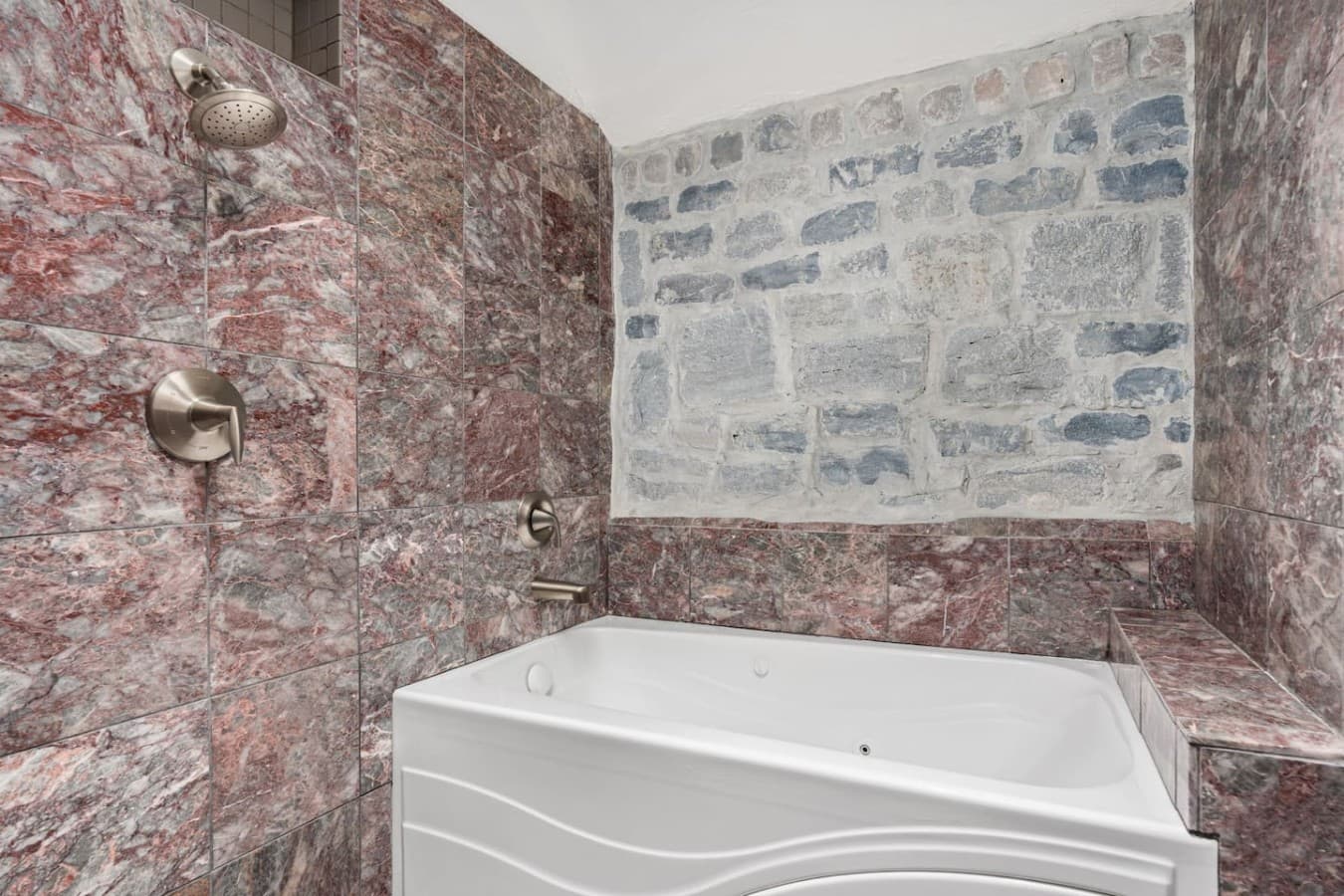 This is the private bathroom inside the room you will be renting offering a deep soaking tub surrounded by elegant stone detail.