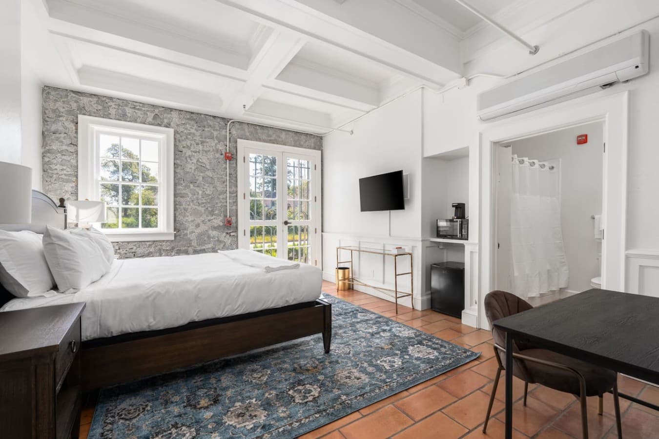 A spacious private room featuring a cozy sleeping area, seating, and convenient in-room amenities.
