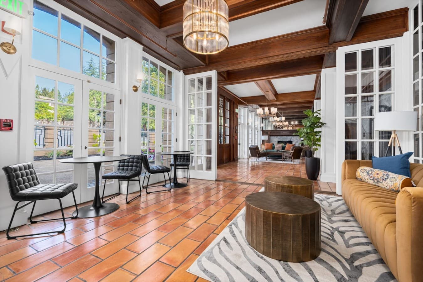 A bright shared sitting area with large windows and relaxed seating located in the hotel’s common space and not inside your private room.