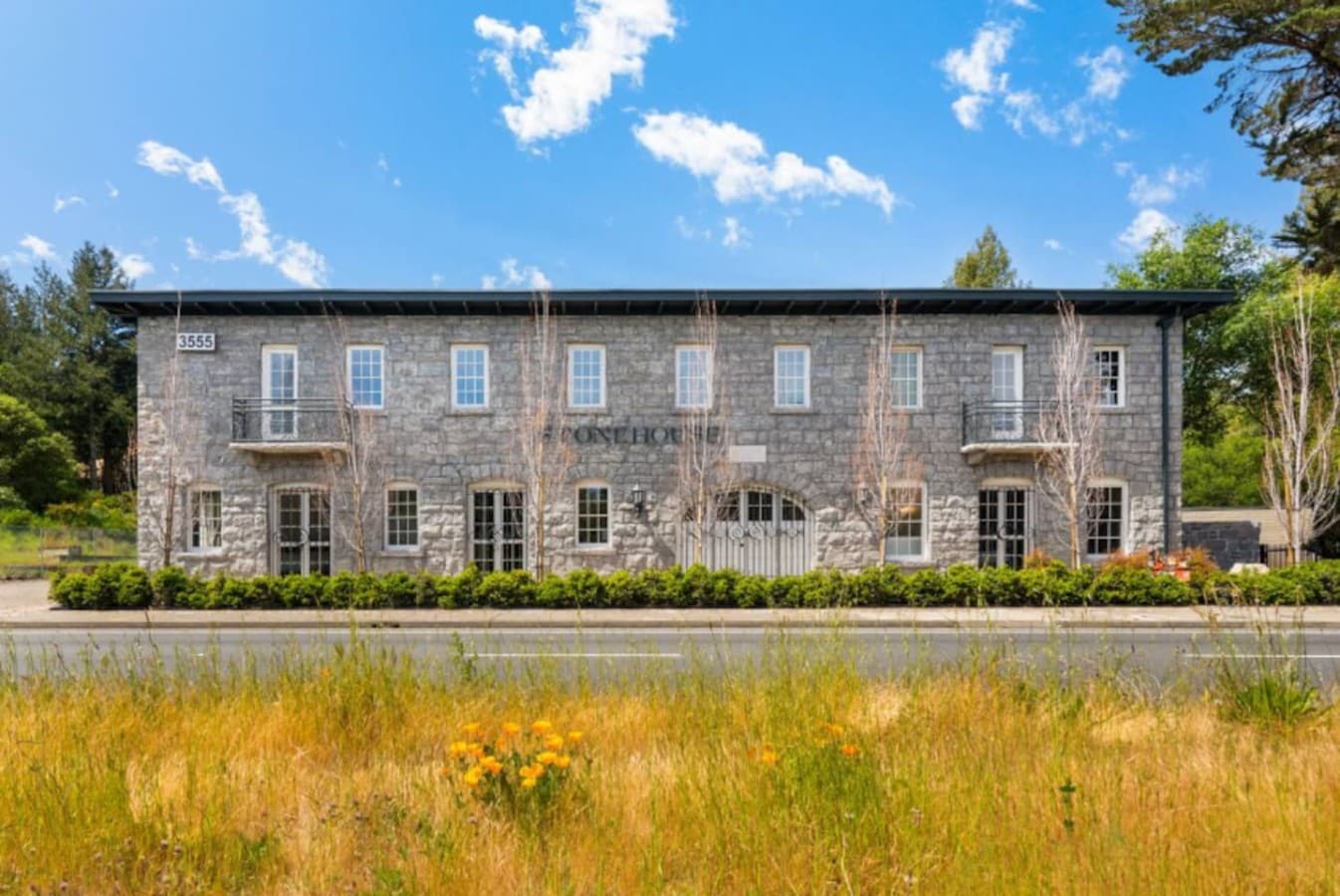 A serene view of the hotel’s historic stone exterior surrounded by open landscape and seasonal wildflowers.