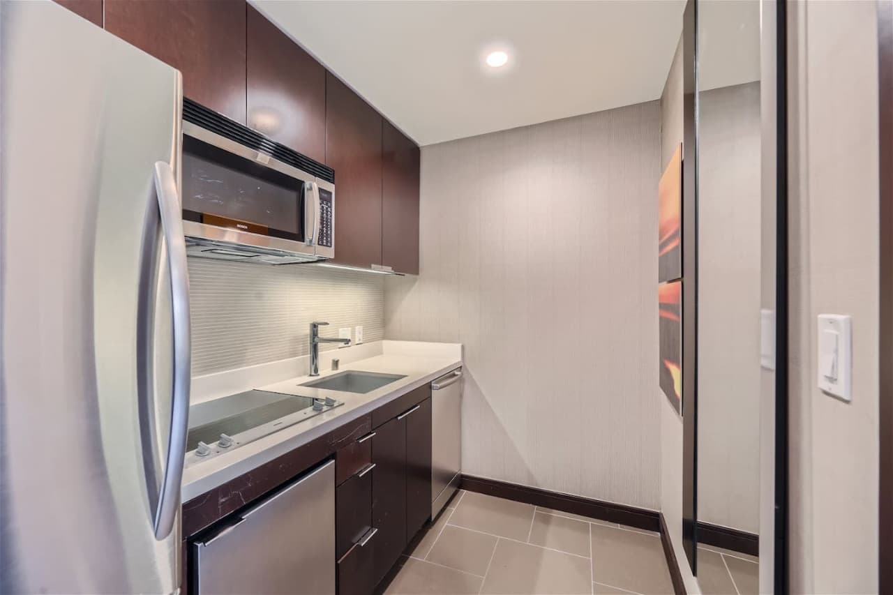 Kitchen with full-sized refrigerator, electric cooktop, microwave, dishwasher, washing machine, and dryer.