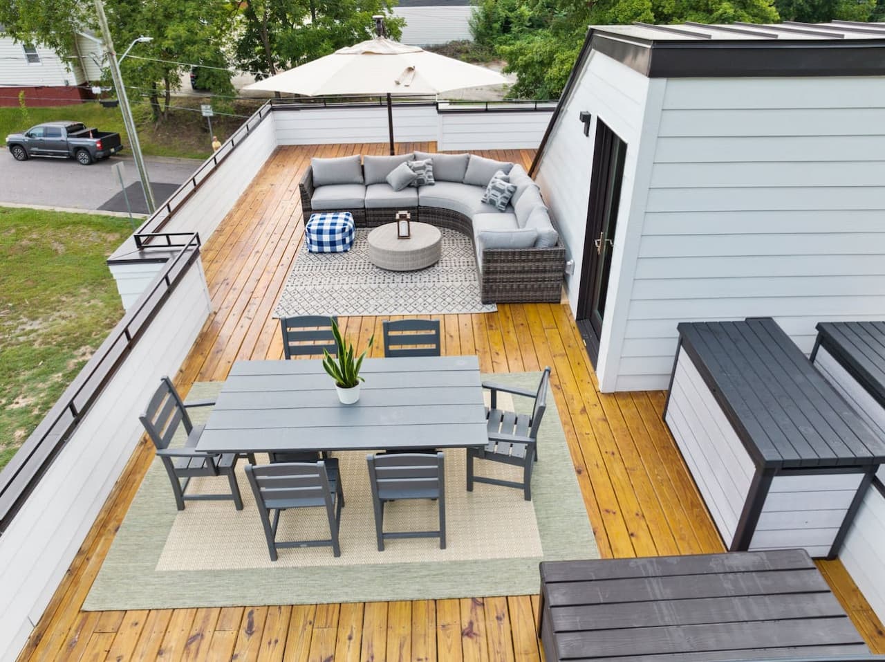 Stunning rooftop oasis featuring a spacious sectional sofa, outdoor rug, and umbrella-shaded lounge area, perfect for relaxing or socializing.