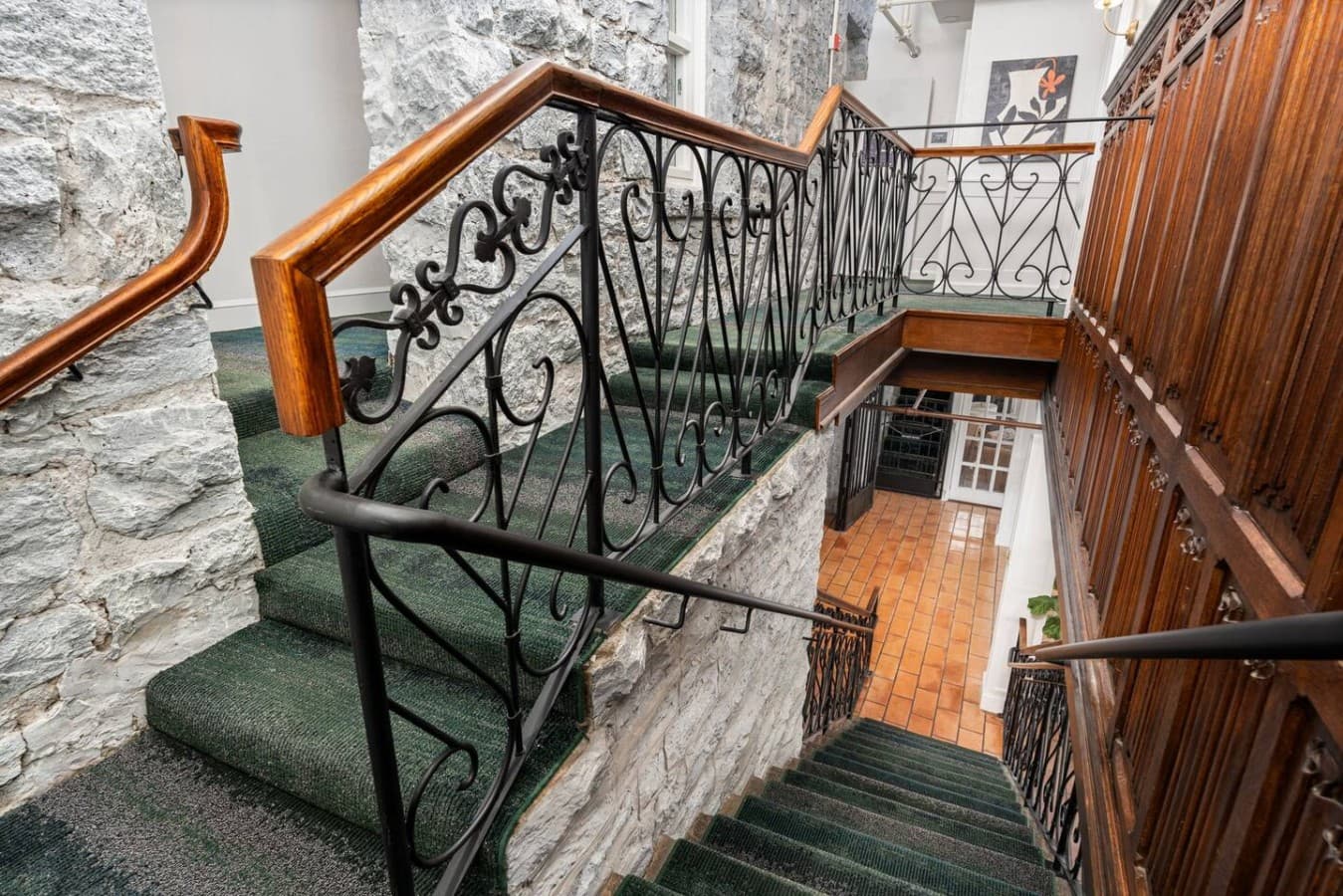 A beautifully detailed shared staircase featuring wrought iron railings and historic stone accents located in the hotel’s common area.