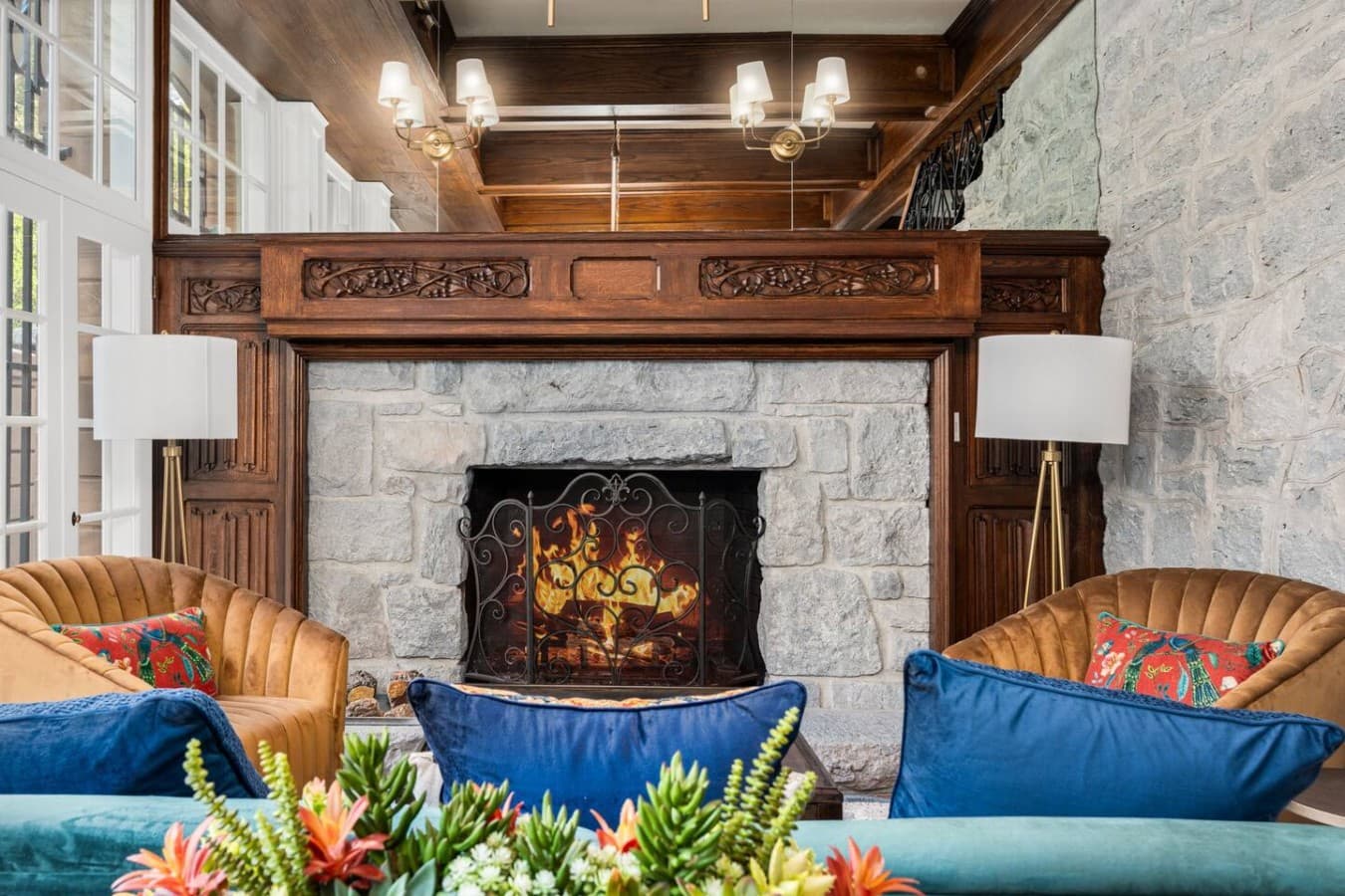 A shared fireplace lounge featuring a classic stone hearth and cozy seating located in the hotel’s common space and not inside your private room.