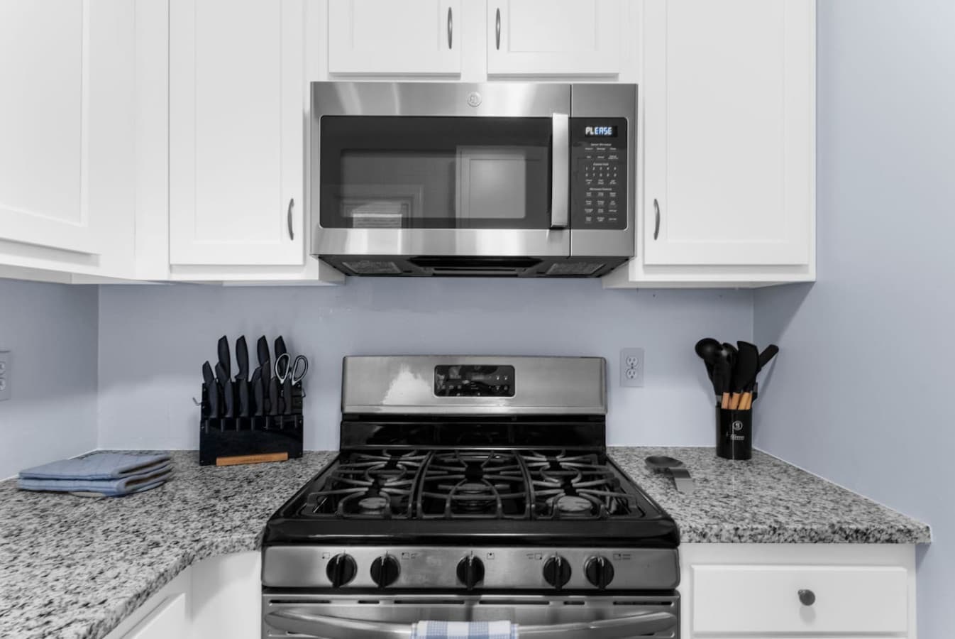 Stainless steel stove and microwave ready for cooking.