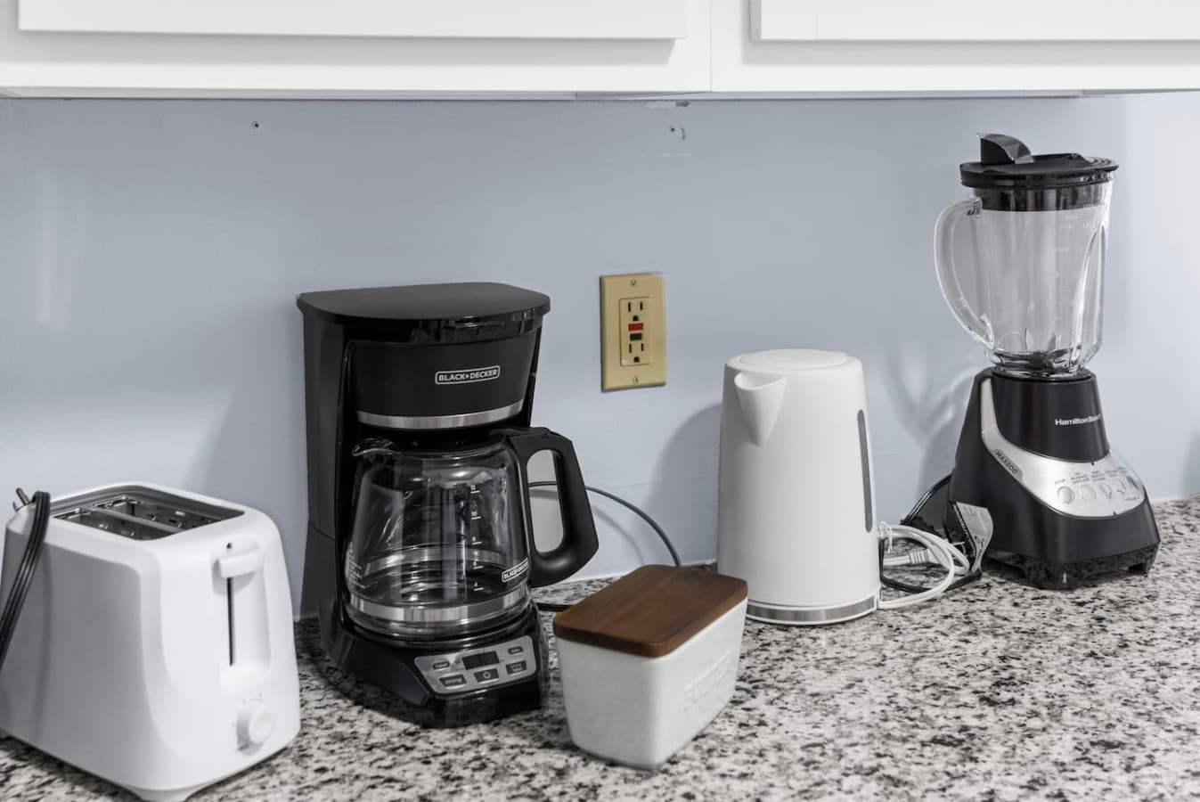 Coffee station with a coffee maker, kettle, and essentials.
