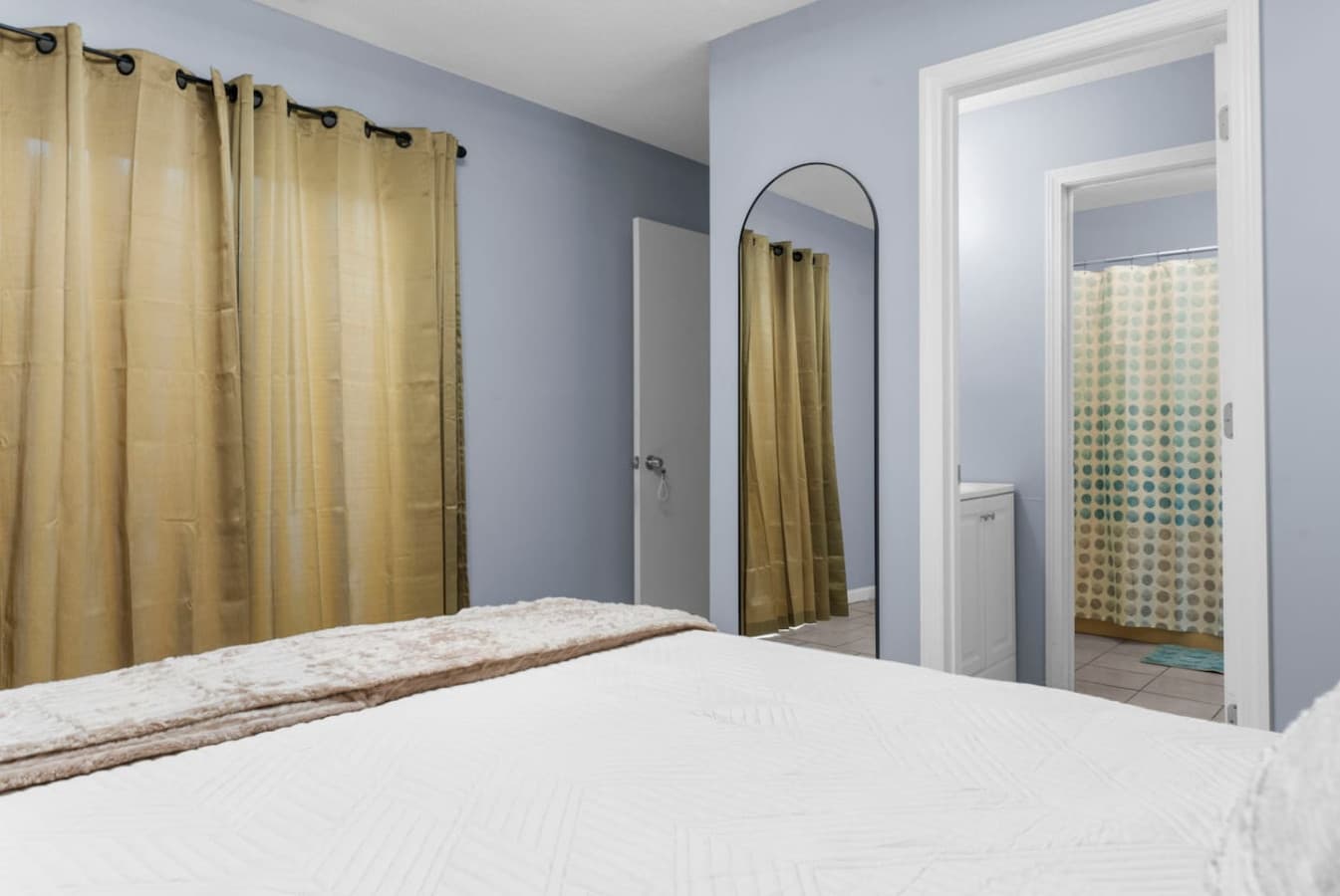 Bedroom with warm accents and a view into the bathroom area.