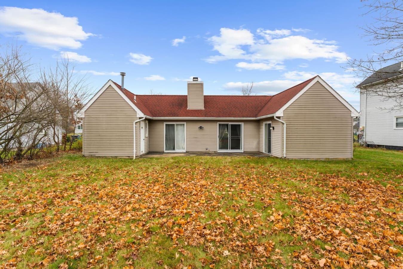 Rear view of the home with a wide lawn and seasonal scenery.