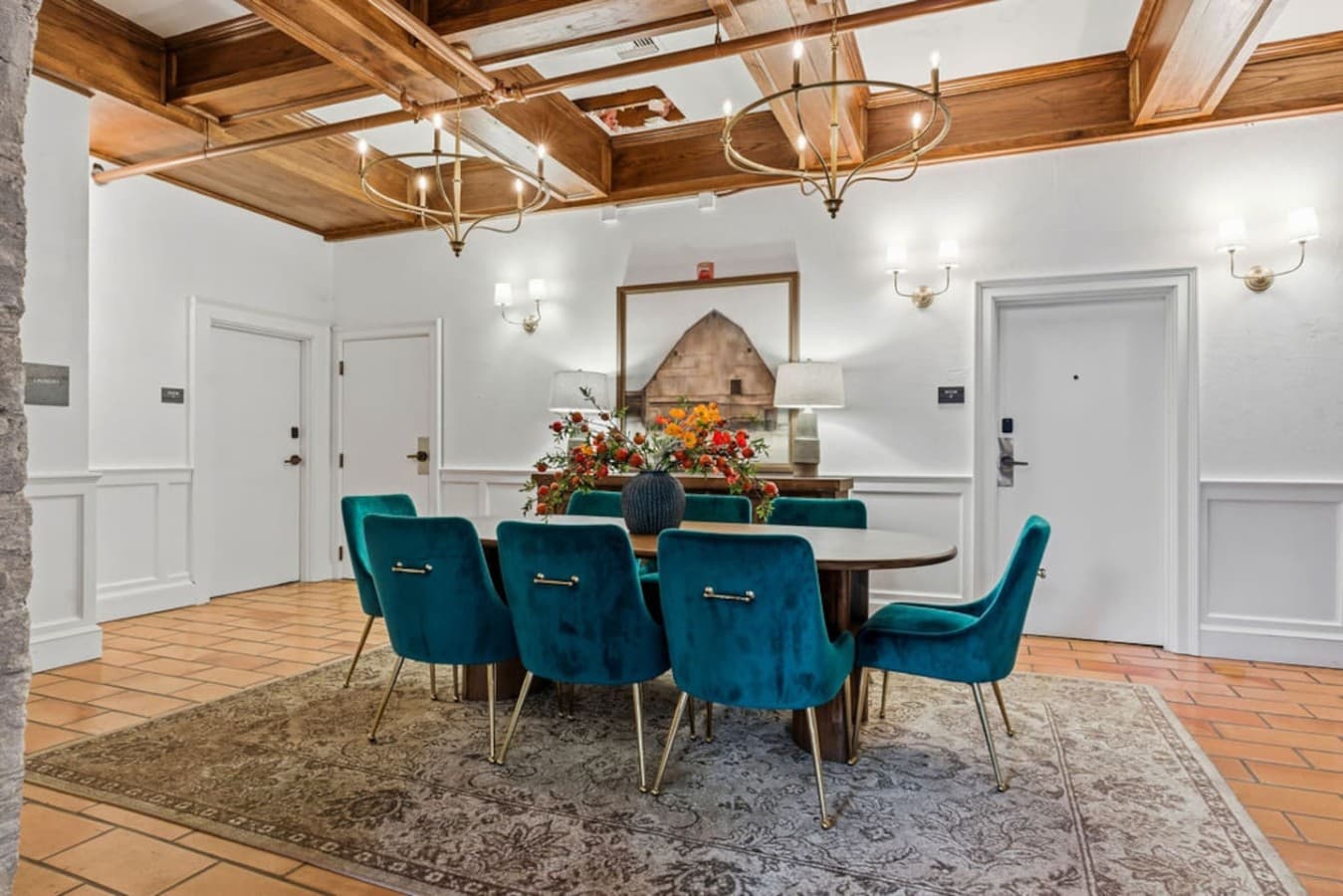 A shared gathering space with a large communal table and artistic stone walls located in the hotel’s common area and not inside your private room.