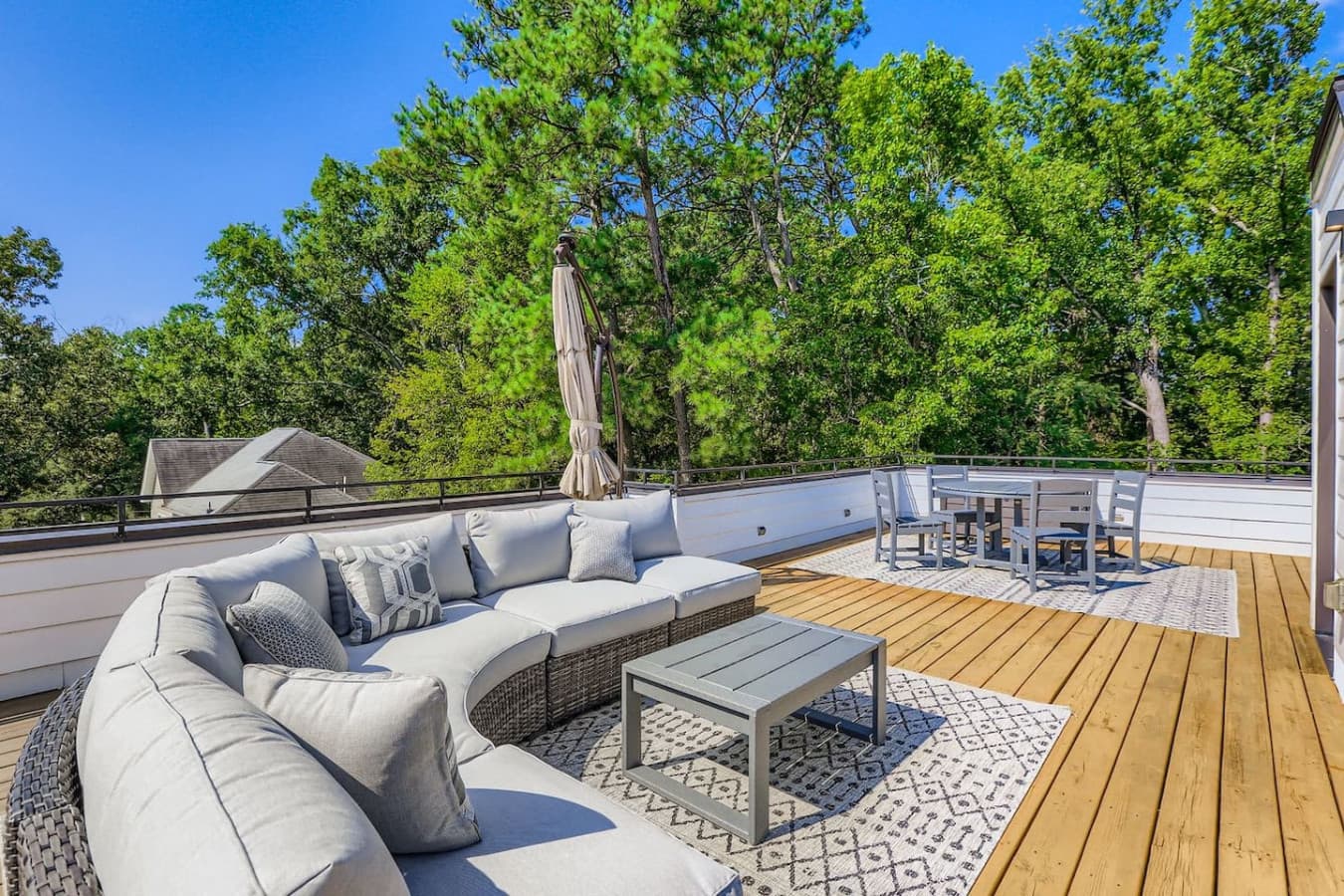 Unit A: Unwind on this stylish rooftop lounge featuring a spacious wicker sectional with plush cushions, a large umbrella for shade, a cozy outdoor rug, and a chic coffee table centerpiece.