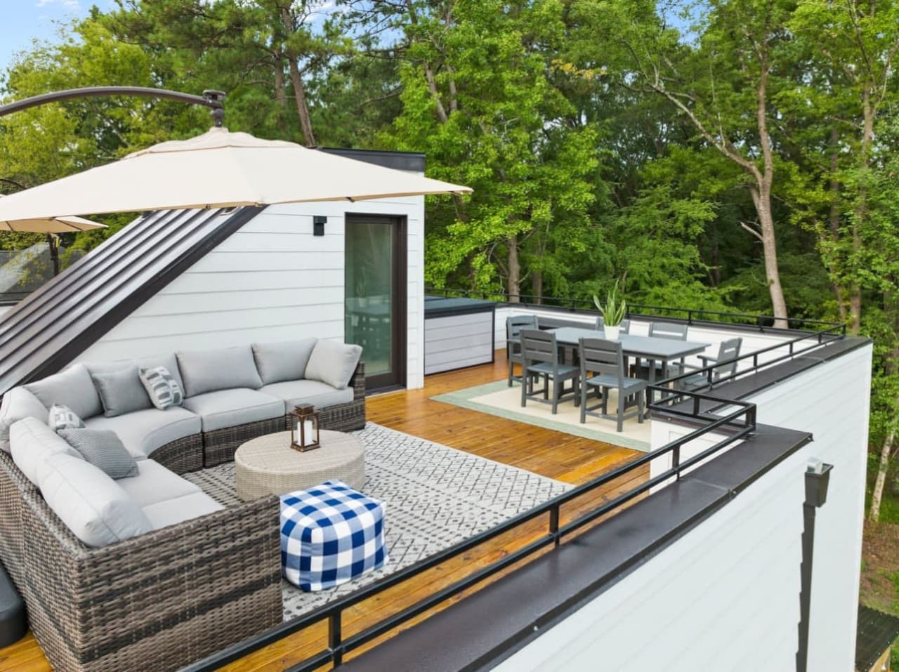 Unit B: Escape to this private rooftop retreat nestled among the trees, featuring a cozy sectional sofa, umbrella-shaded lounge area, and stylish dining setup for six.