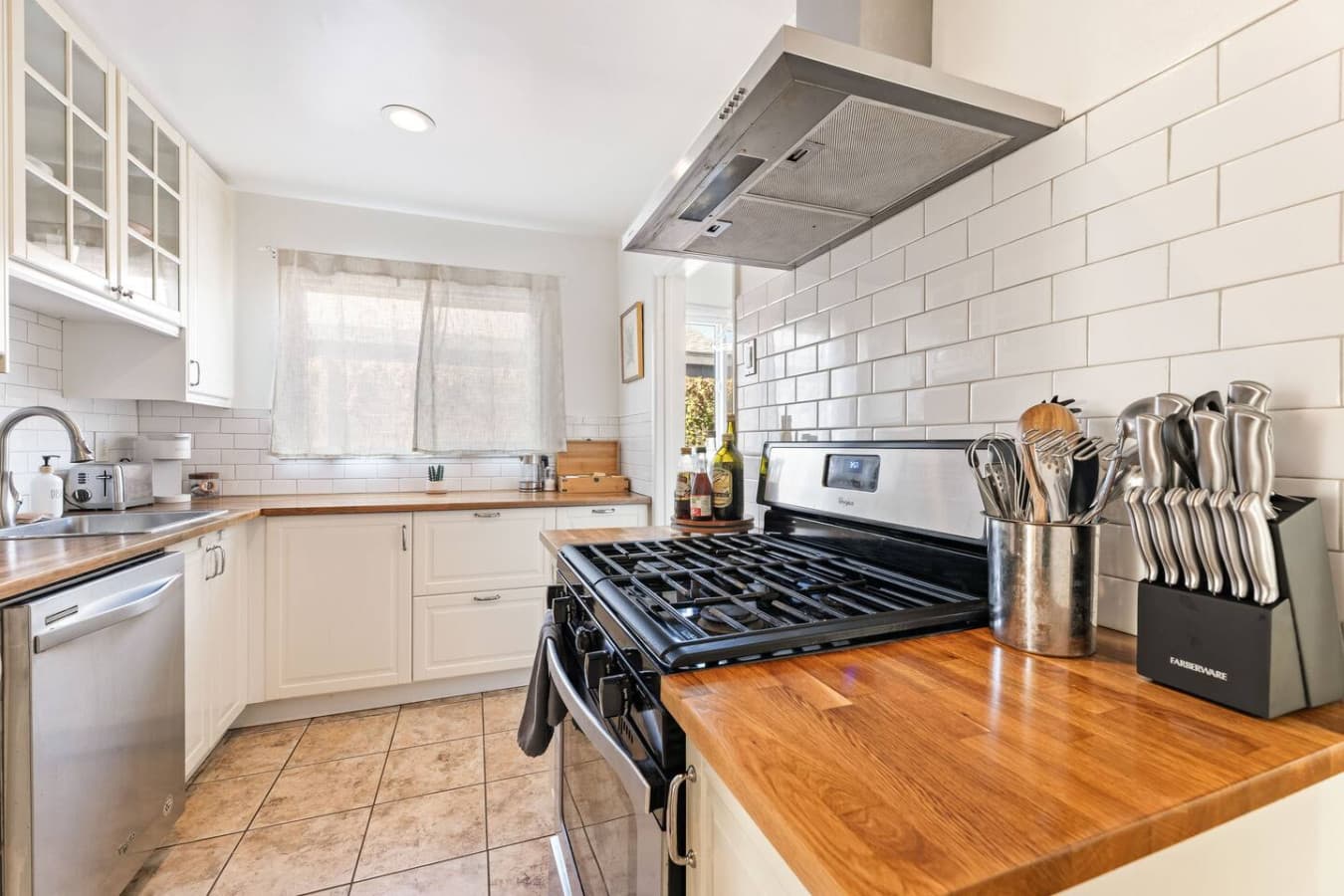 Fully equipped kitchen with gas range, stainless hood, and beautiful wood countertops.