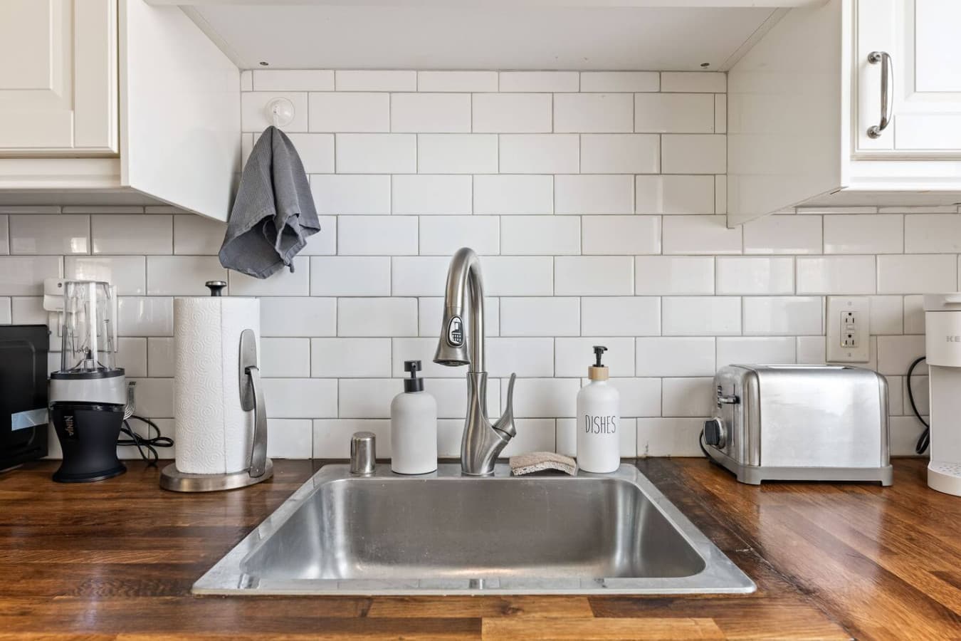 Bright kitchen sink area with subway tile backsplash and convenient small appliances for everyday comfort.