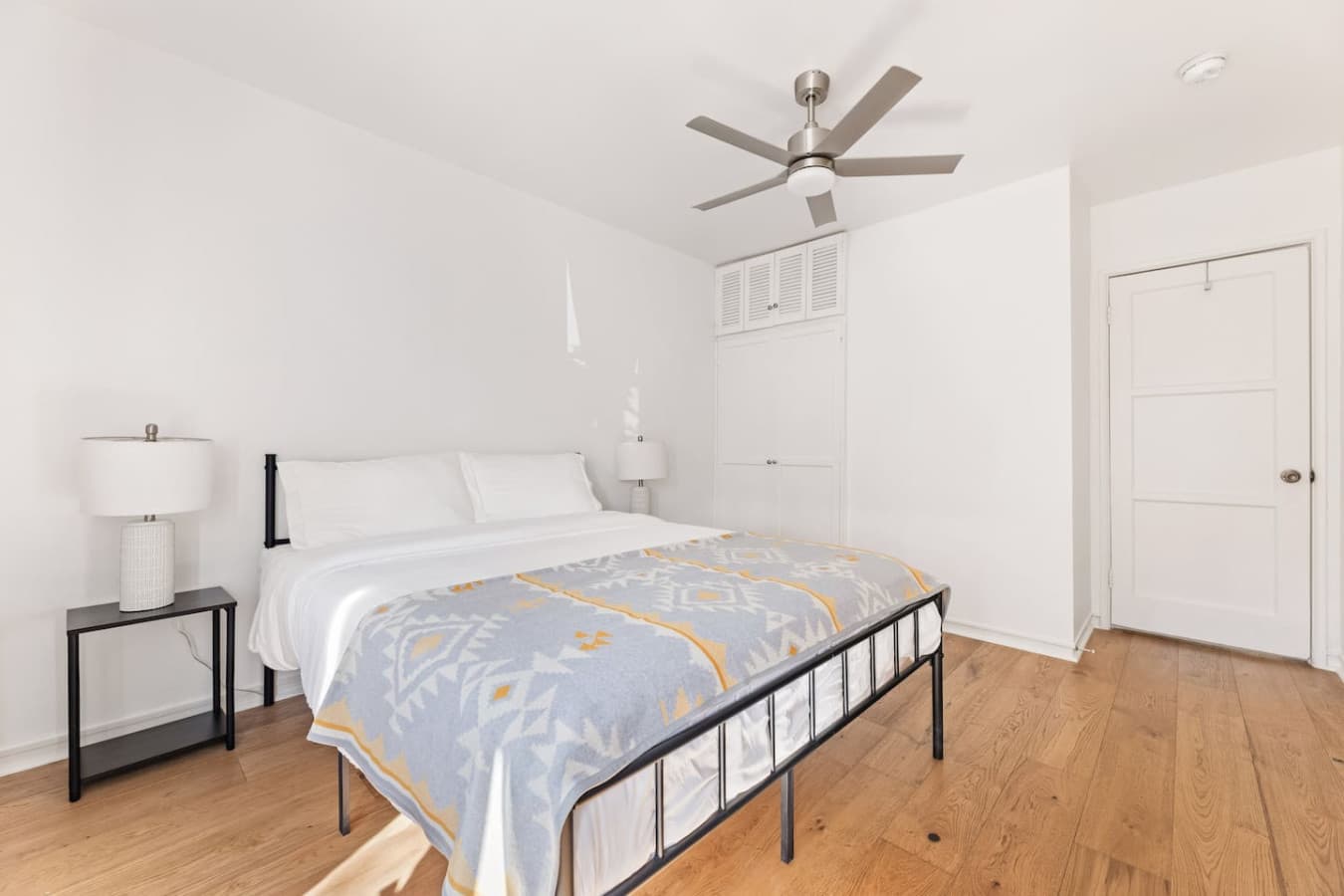 Peaceful bedroom with crisp white bedding and a ceiling fan for added comfort.