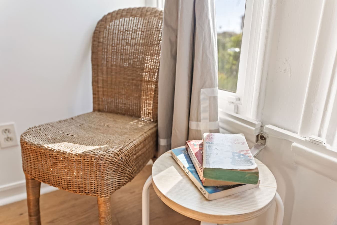 Sunny corner reading nook with woven chair and curated books.