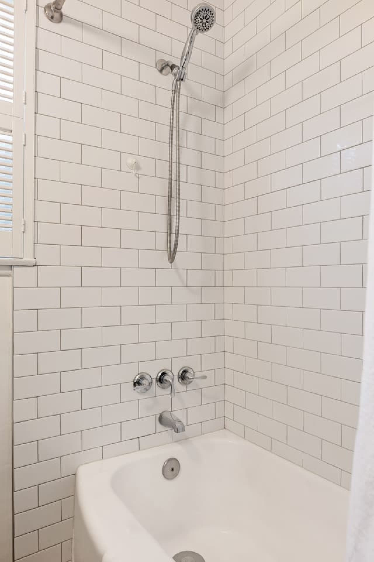 Clean white tile shower and tub combination with modern fixtures.