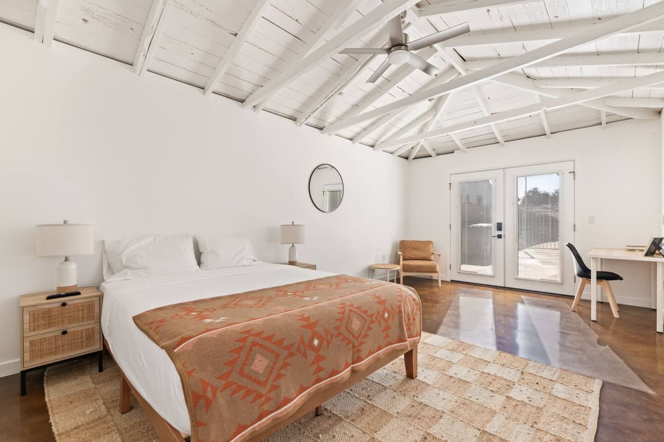 Spacious bedroom with exposed beams and direct access to the outdoor patio.