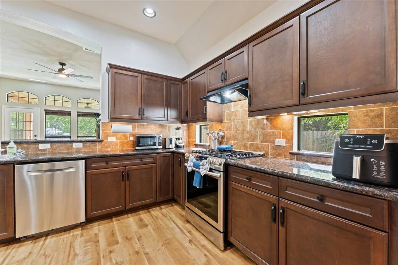 Modern kitchen featuring granite countertops, stainless steel appliances, and warm wood cabinetry.