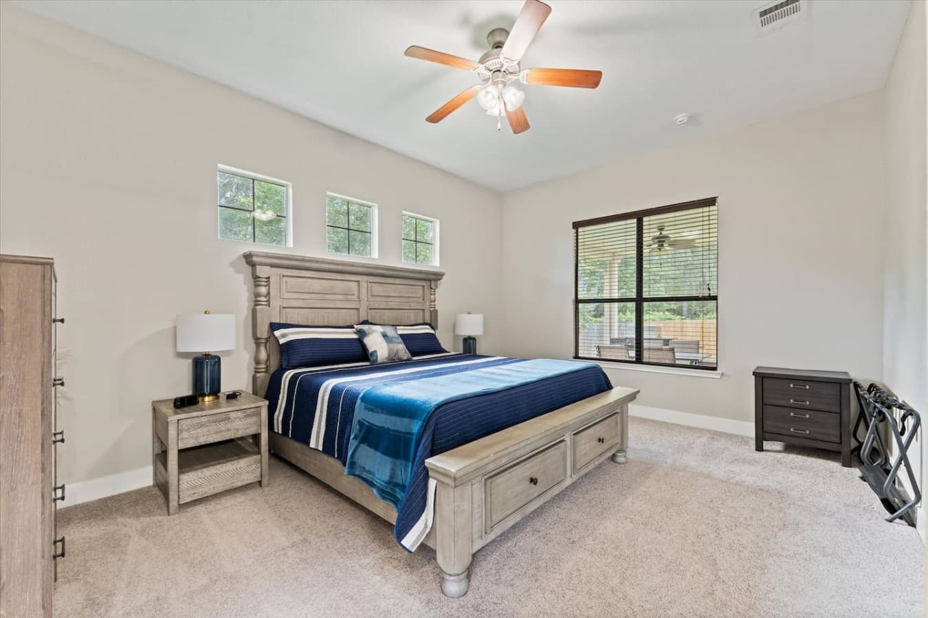 Spacious bedroom featuring a plush bed, soft carpeting, and large windows with natural light.