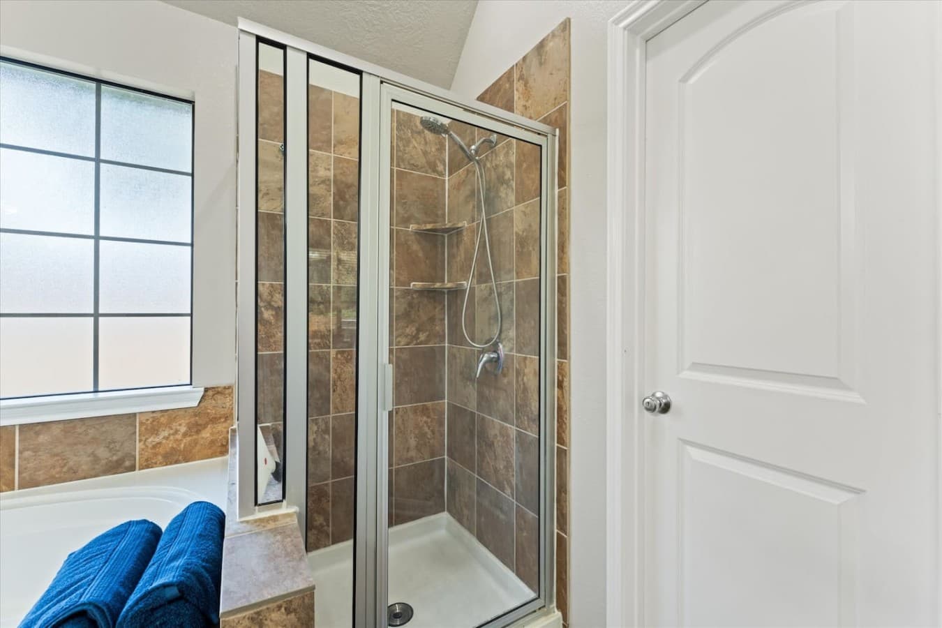 Walk in glass shower with tiled finishes and a bright, modern design.