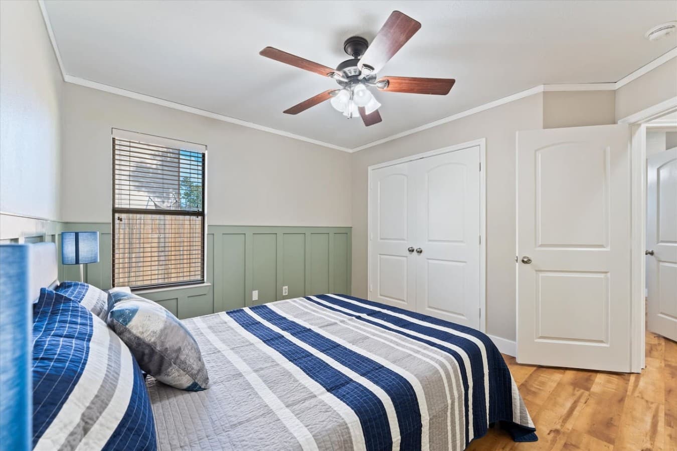 Comfortable bedroom with stylish accent walls, warm wood flooring, and plenty of natural light.