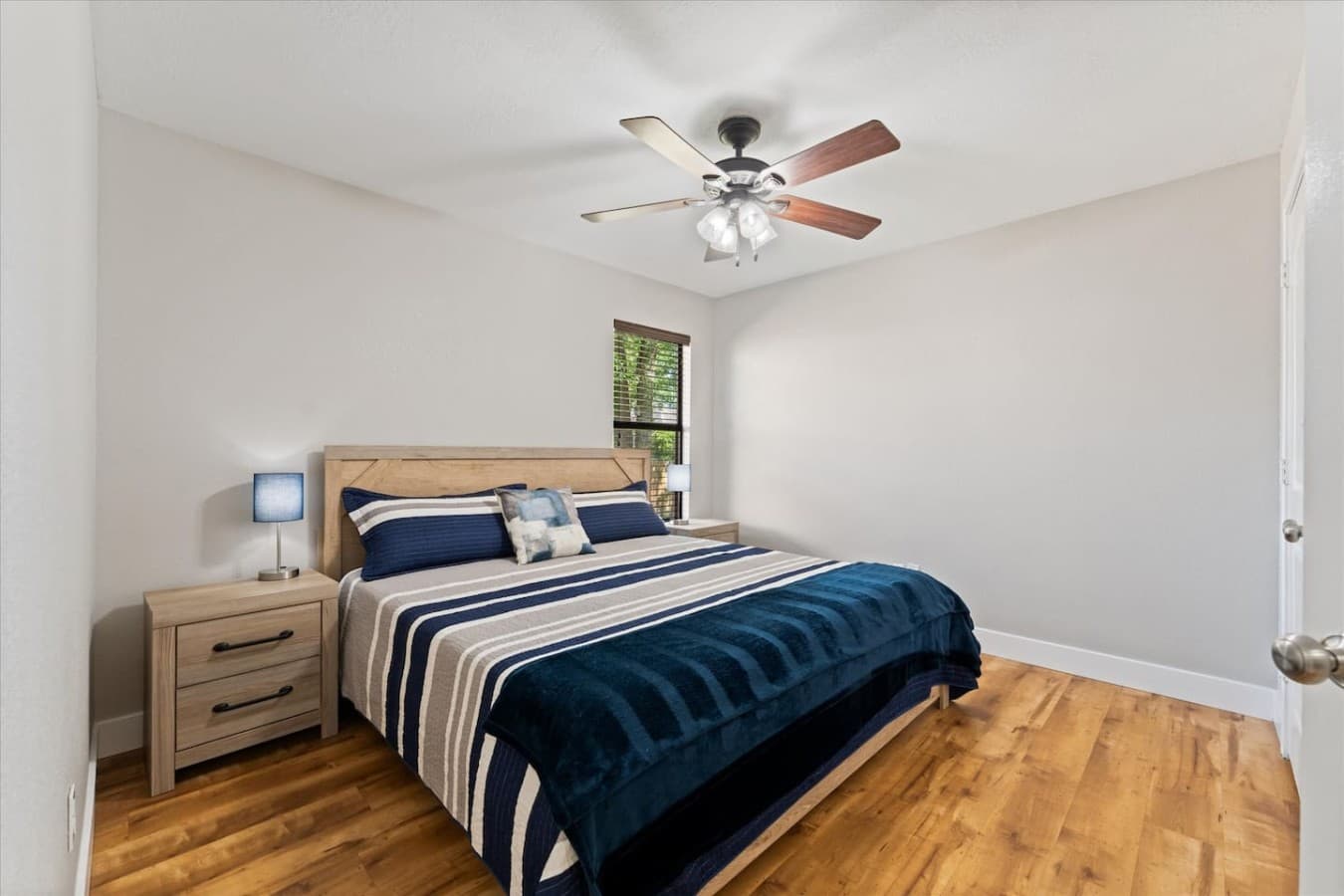 Cozy bedroom with warm wood flooring, soft lighting, and a comfortable bed for restful nights.