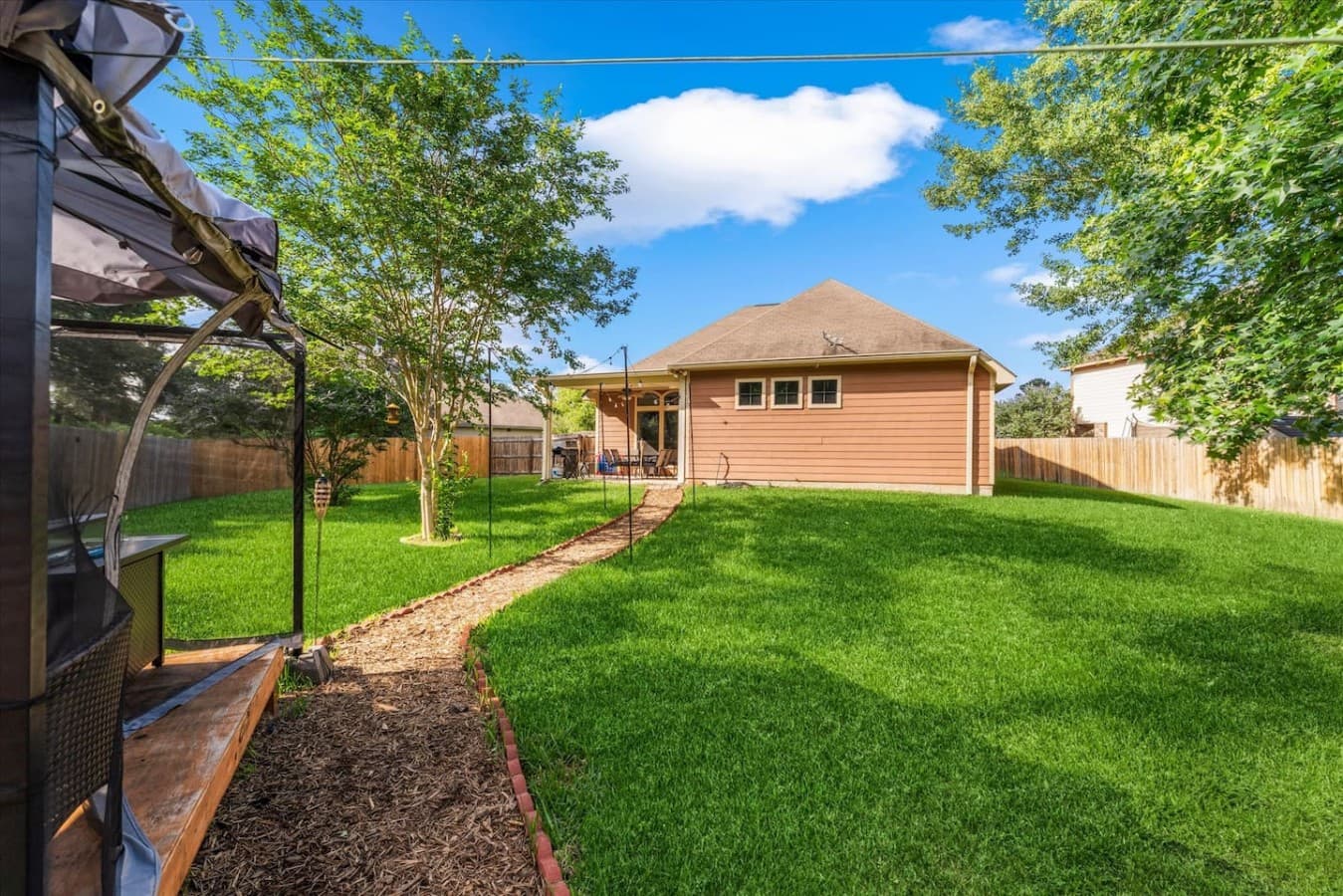 Backyard pathway leading through the spacious yard to a cozy outdoor gathering space.