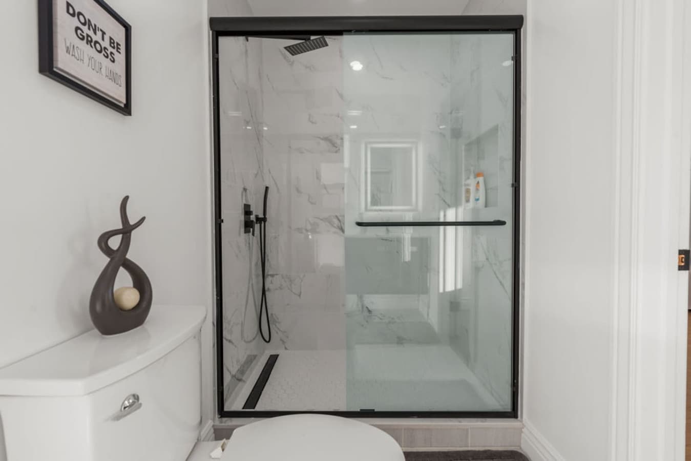 Spacious walk in shower with sleek glass doors and contemporary tile design.