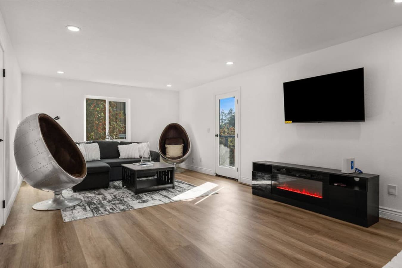 The Private In Law Suite living room offers a bright and open space with modern seating and a wall mounted TV.