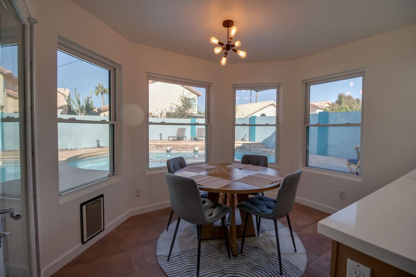 Sunlit breakfast nook surrounded by large windows.