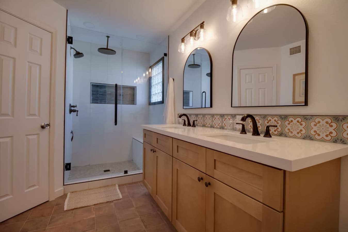 Large bathroom with dual sinks and glass enclosed shower.