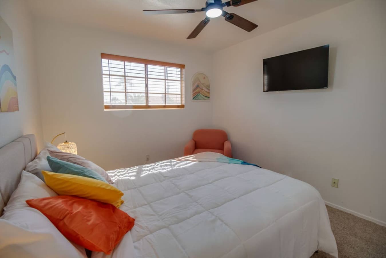 Bright bedroom with comfortable bed and wall mounted TV.