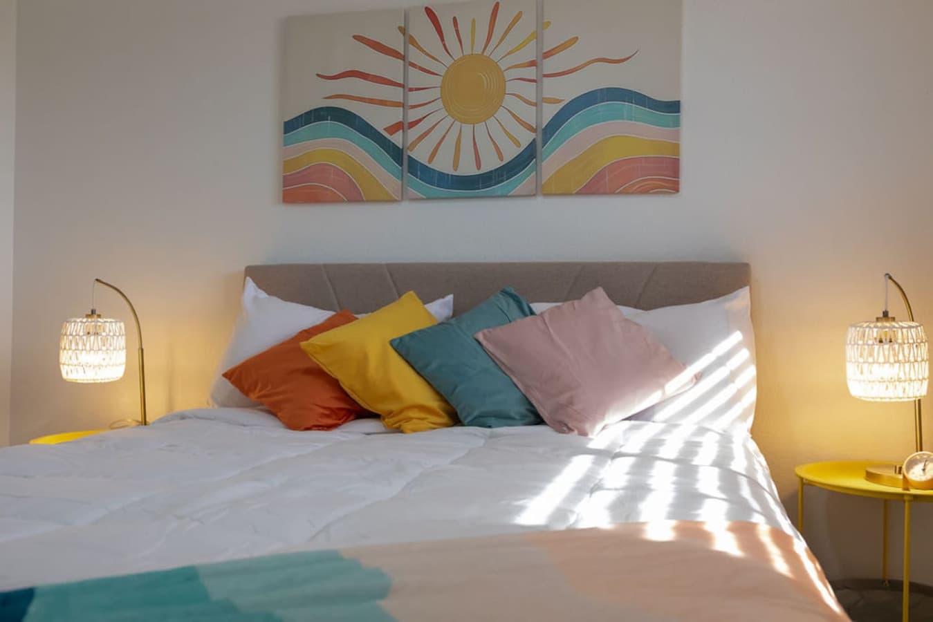 Queen bed styled with colorful pillows and cheerful artwork.
