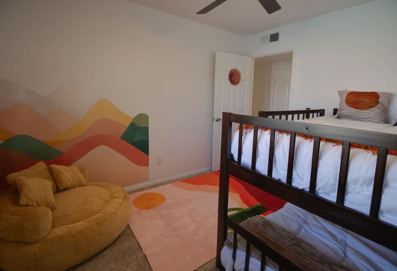 Playful bunk room with soft seating and colorful wall art.
