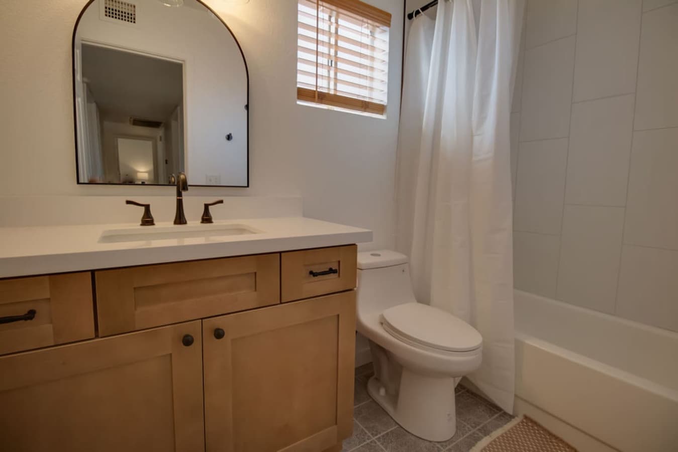 Clean and functional bathroom with shower tub combo and vanity storage.