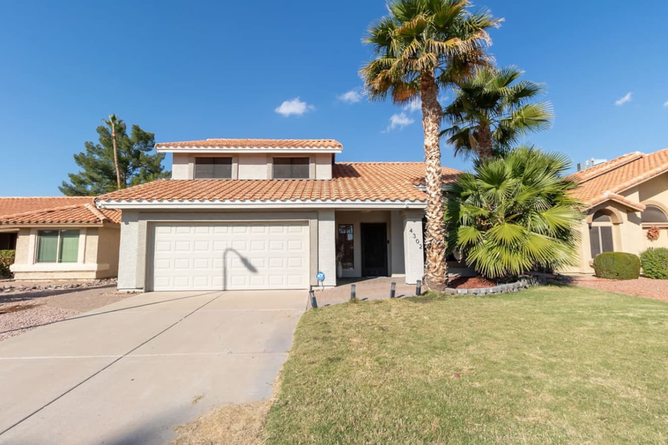 Front exterior with driveway parking and desert landscaping.