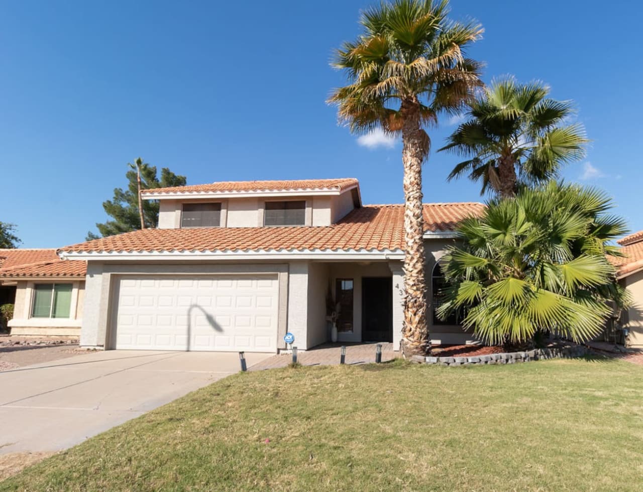 Welcoming home exterior with palm trees and attached garage.