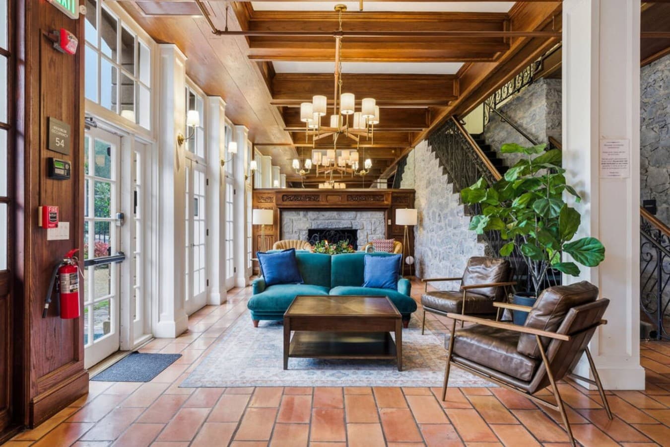 A bright and elegant shared lounge featuring cozy seating, warm wood accents, and large windows that fill the space with natural light.