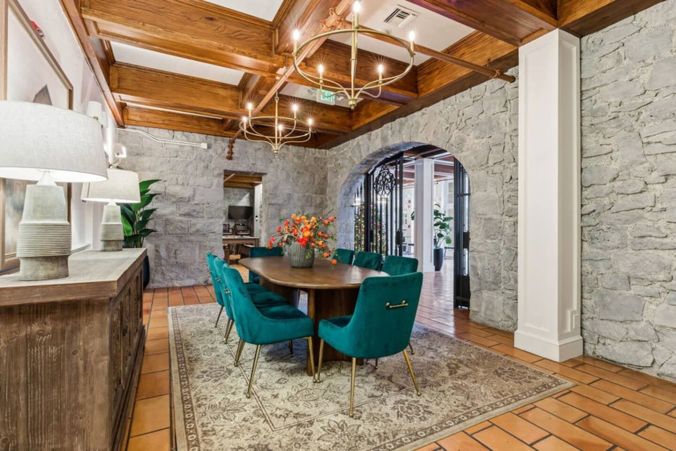 An inviting shared dining space featuring rich stone walls, warm wood ceilings, and vibrant seating creating a stylish setting for meals and conversation.