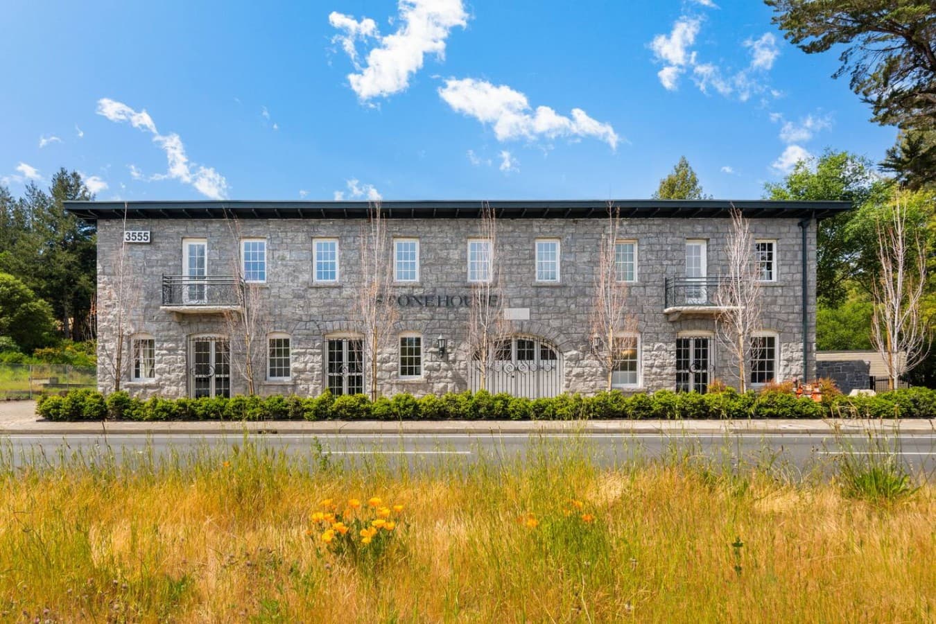 A serene view of the hotel’s historic stone exterior surrounded by open landscape and seasonal wildflowers.